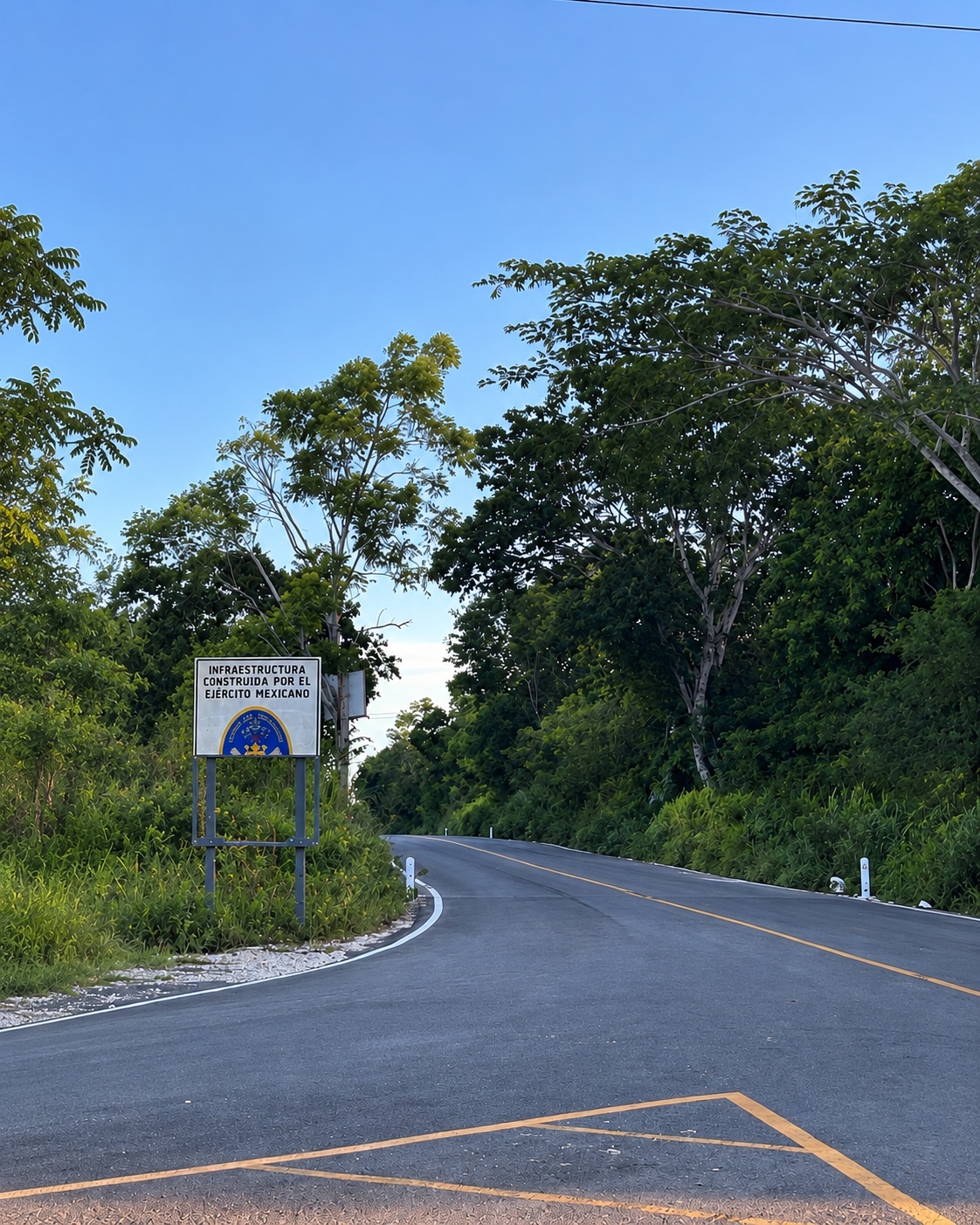 Carretera entre vegetación con señalética de infraestructura militar